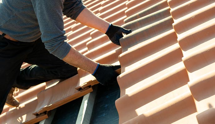 Closeup ofworker hands installing yellow ceramic roofing tiles